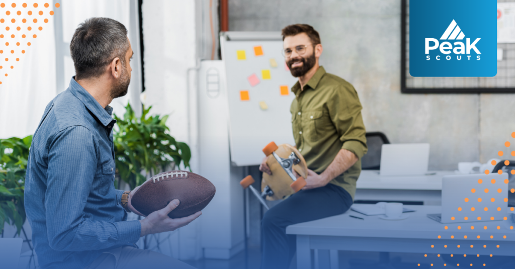 Two sports professionals sit talking and asking questions in the office holding a football and skateboard respectively
