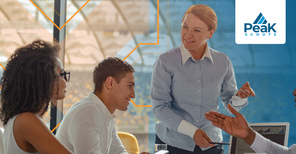 A member from the leadership team addresses two colleagues in a meeting, with a sports stadium visible in the background.